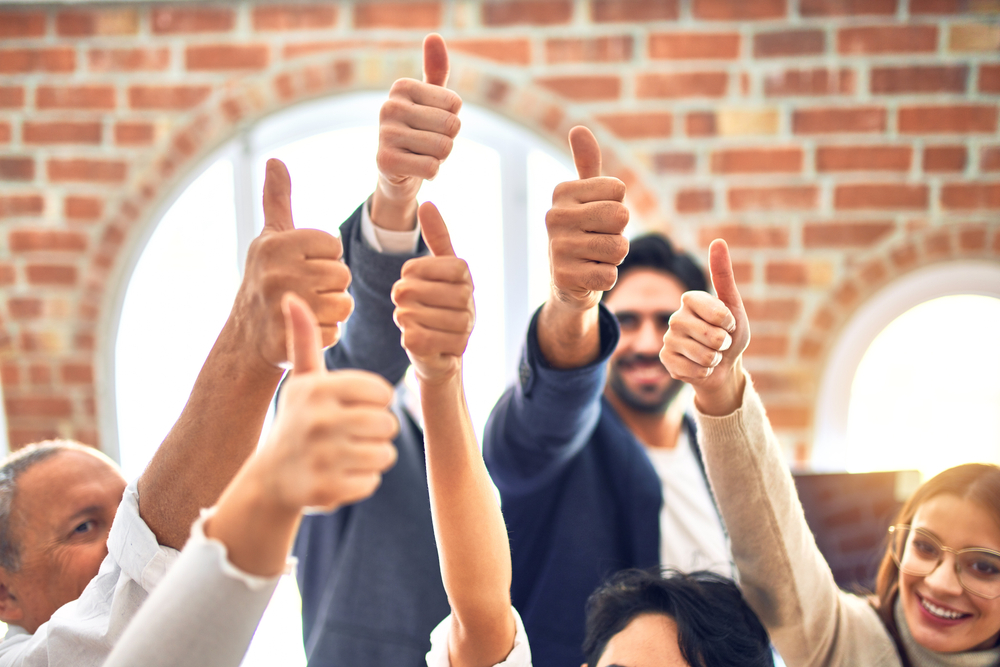 corporate employees smiling while giving thumbs up