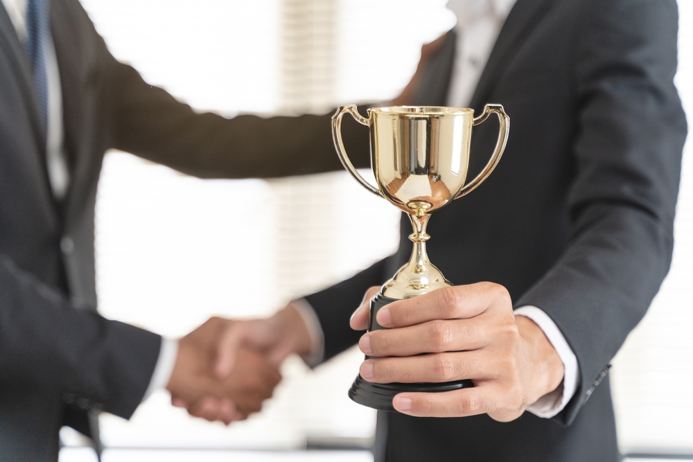 two male on corporate suit shaking hands during company awarding