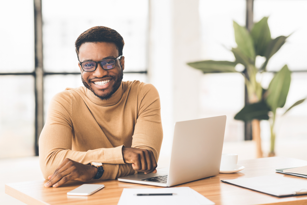 smiling hr recruiter sitting with his laptop, phone, pen, and papers on table