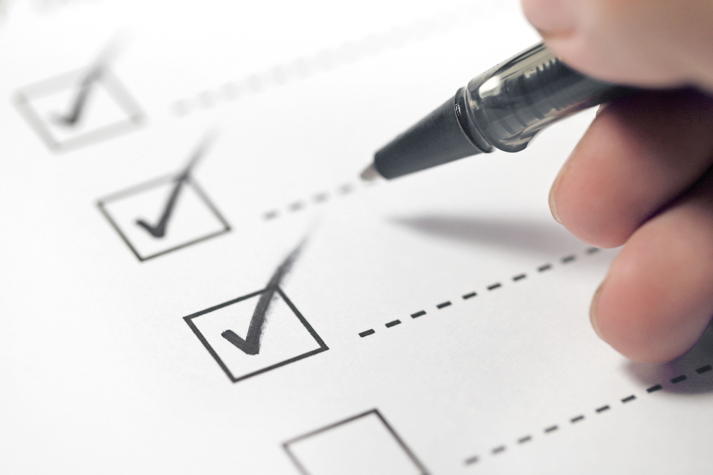 Hand with black pen marking on checklist boxes