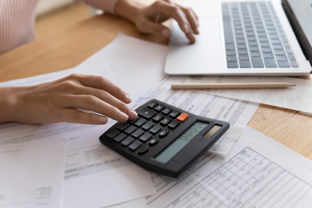 close up of woman calculating using a calculator and papers