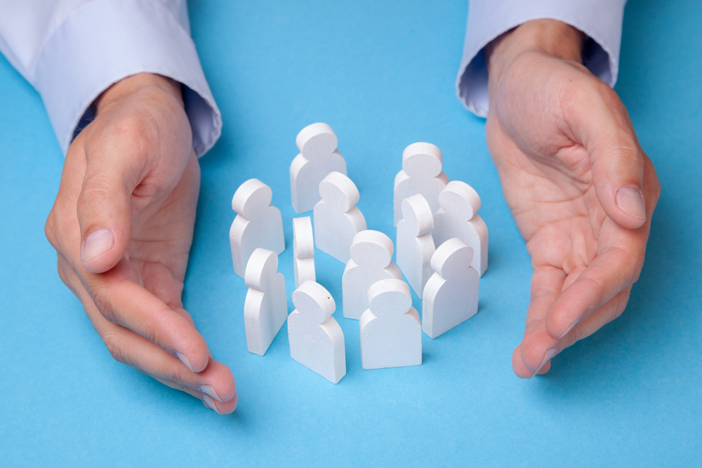 hands circled around a group of human wooden figures