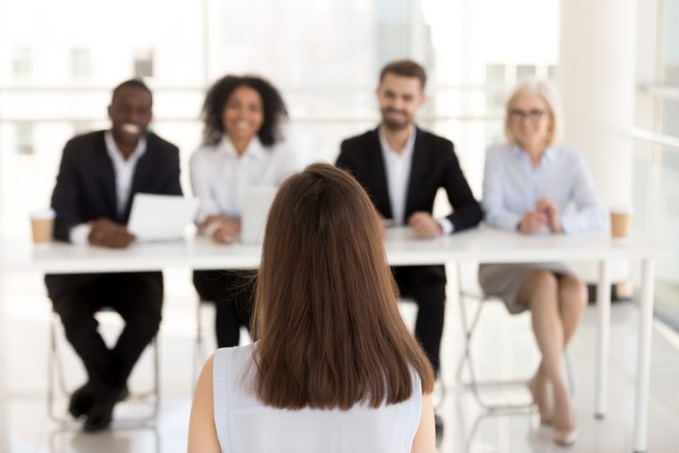 Back view of female job candidate making a good candidate experience with four recruiters