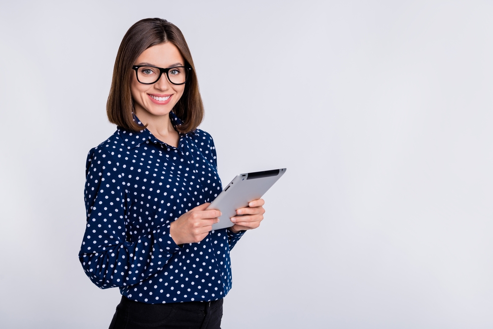 smiling female recruiter while holding a tablet and standing in front of white background