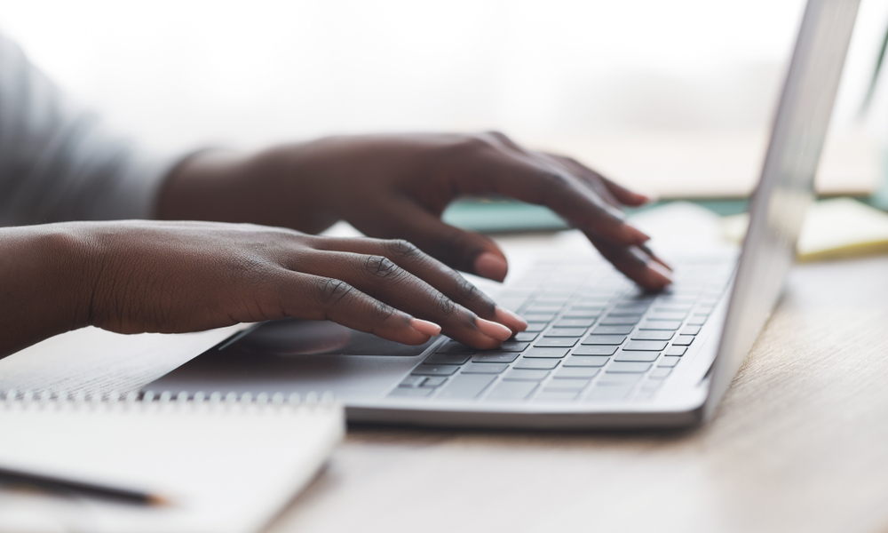 Closeup of hands of an afro woman typing on laptop keyboard