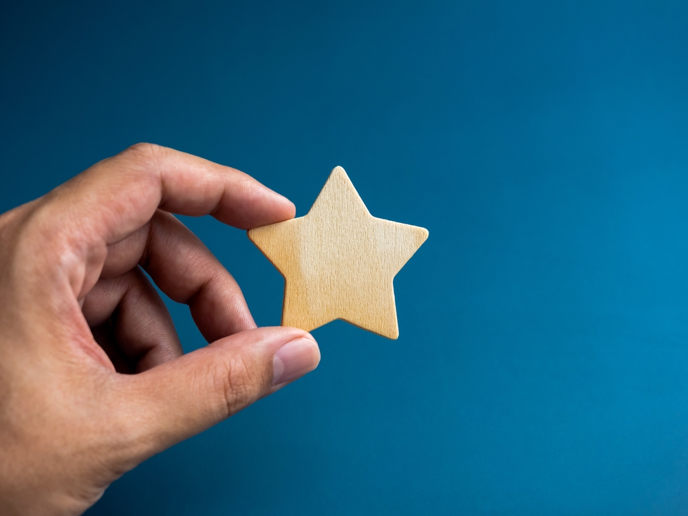 a hand holding a wooden star on blue background