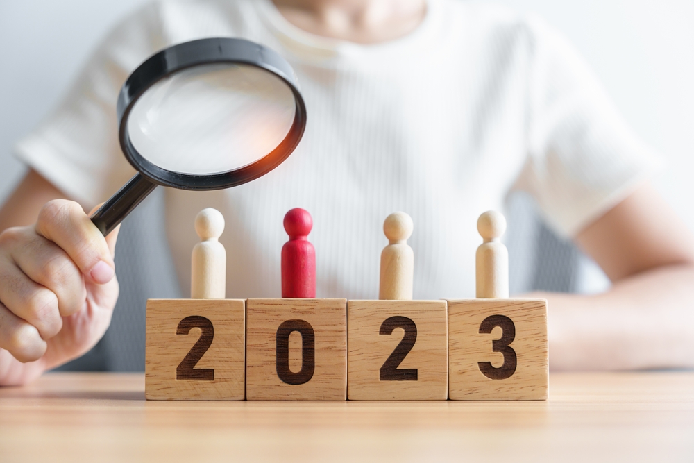 recruiter looking through magnifying on wooden blocks of 2023 and people