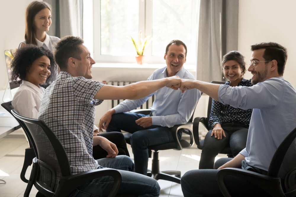 Male colleagues fist bumping at group meeting