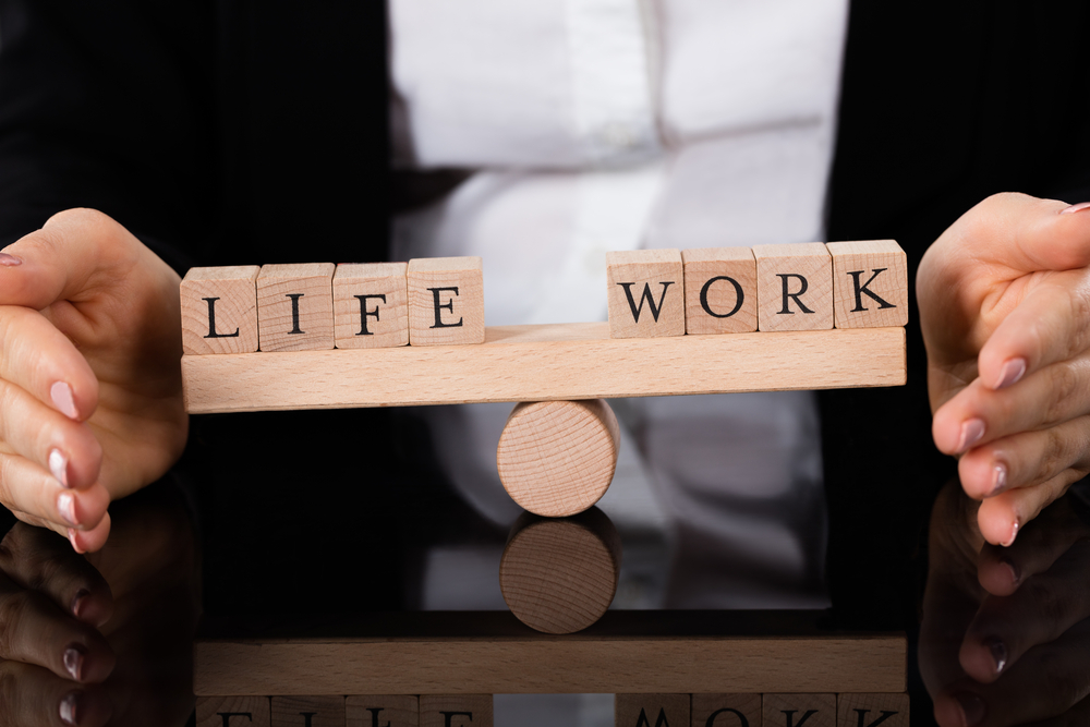 Words LIFE and WORK written on wooden blocks while balancing on a seesaw