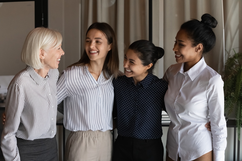 female employees of different ages laughing in a workplace