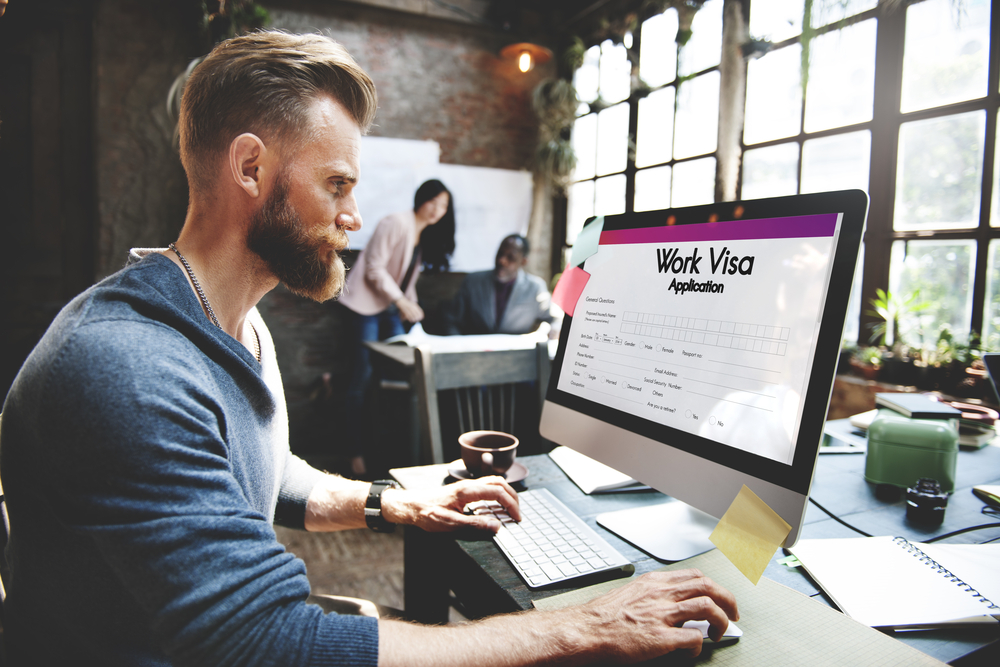 man filling up work visa application on a computer