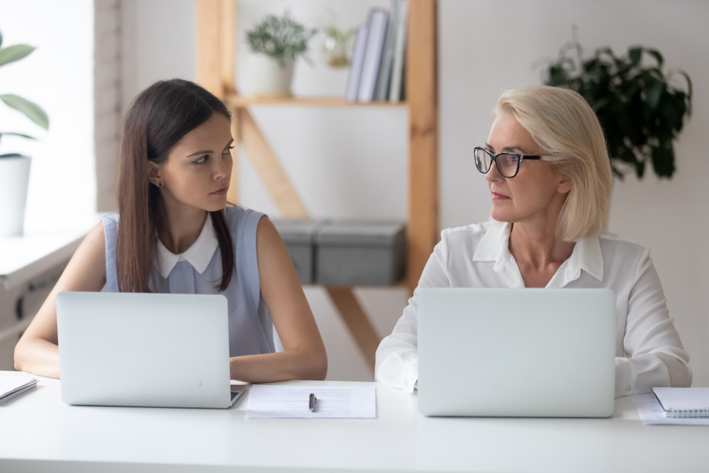 young and old woman sitting beside each other in a workplace