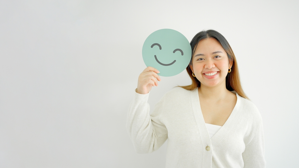 an employee holding a smiley face emoji paper card